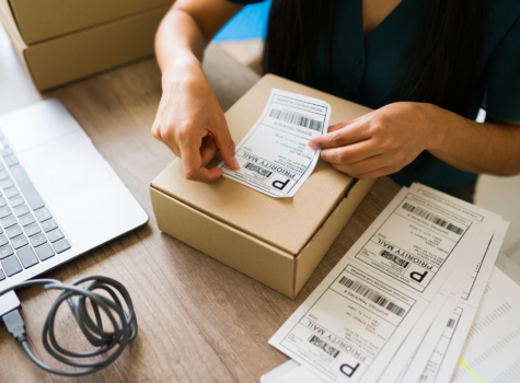 A woman adds a shipping label to a package.