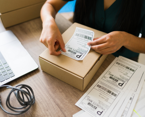 A woman adds a shipping label to a package.