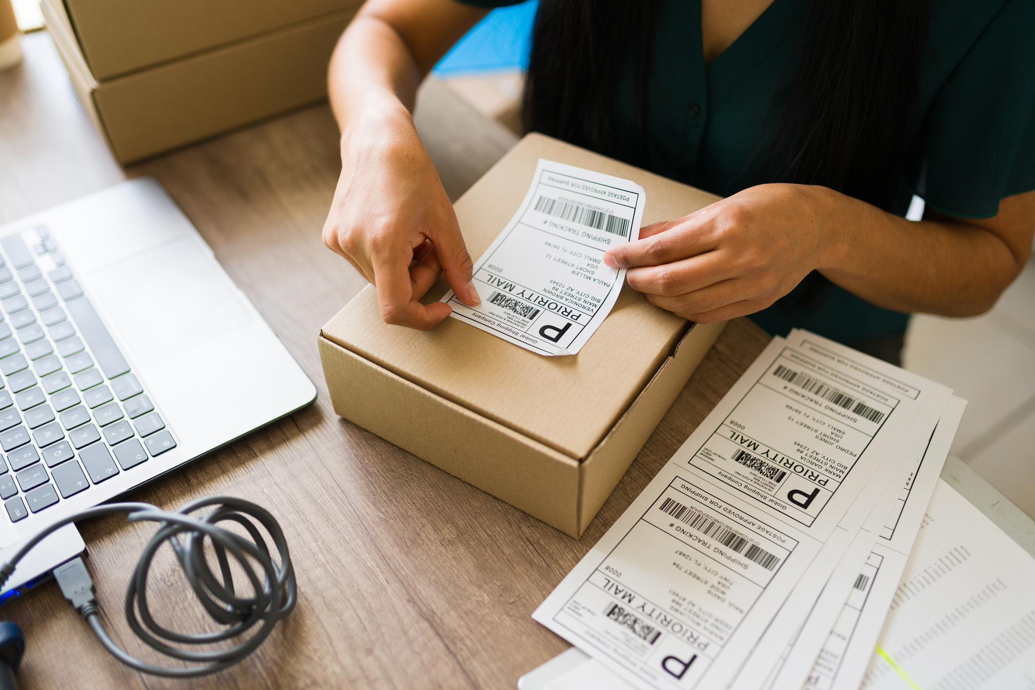 A woman adds a shipping label to a package.