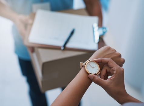 A person looks at their watch before signing for a package.