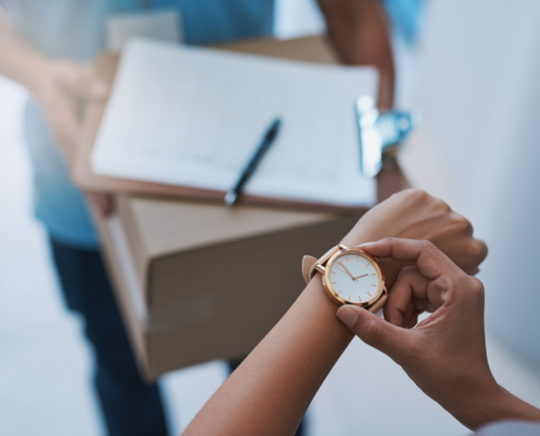 A person looks at their watch before signing for a package.