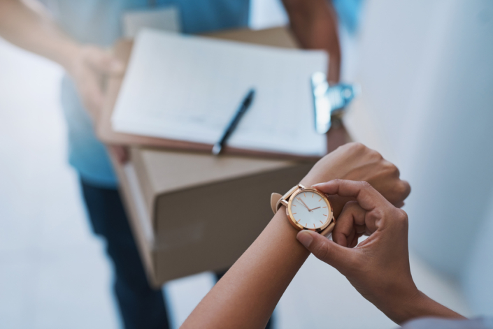 A person looks at their watch before signing for a package.