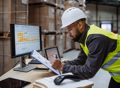 Man in a warehouse looking at shipping data