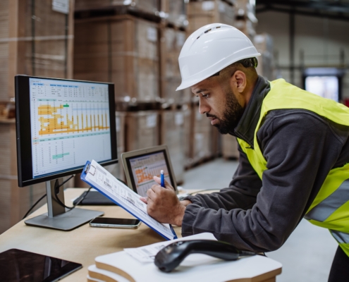 Man in a warehouse looking at shipping data