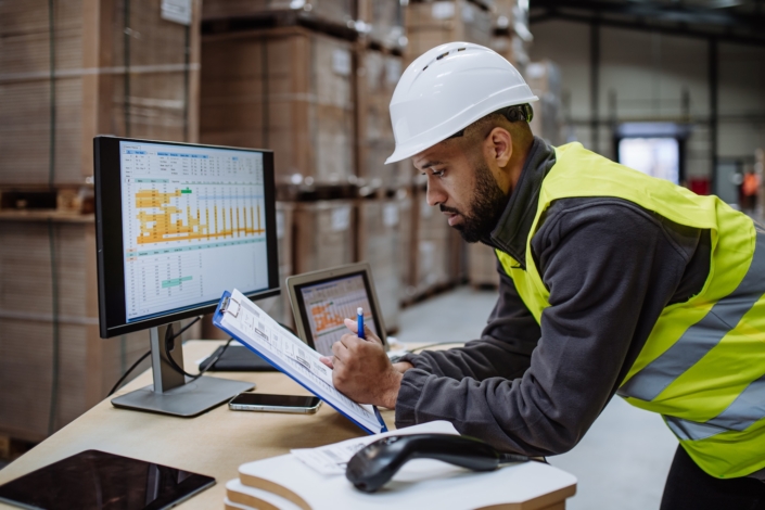 Man in a warehouse looking at shipping data