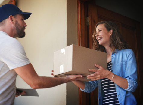 Delivery driver handing package to smiling woman