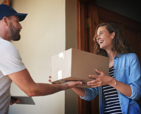 Delivery driver handing package to smiling woman