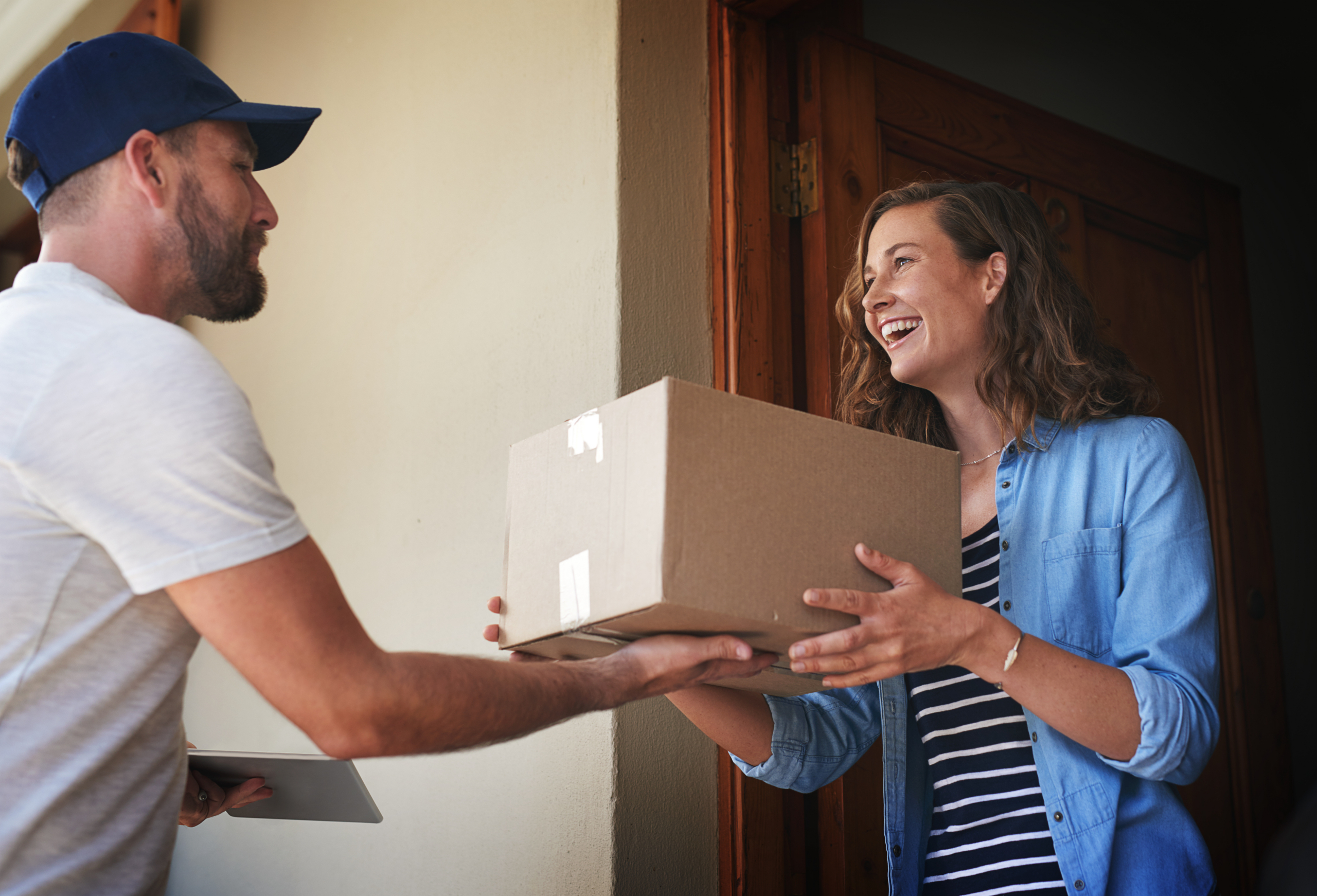 Delivery driver handing package to smiling woman